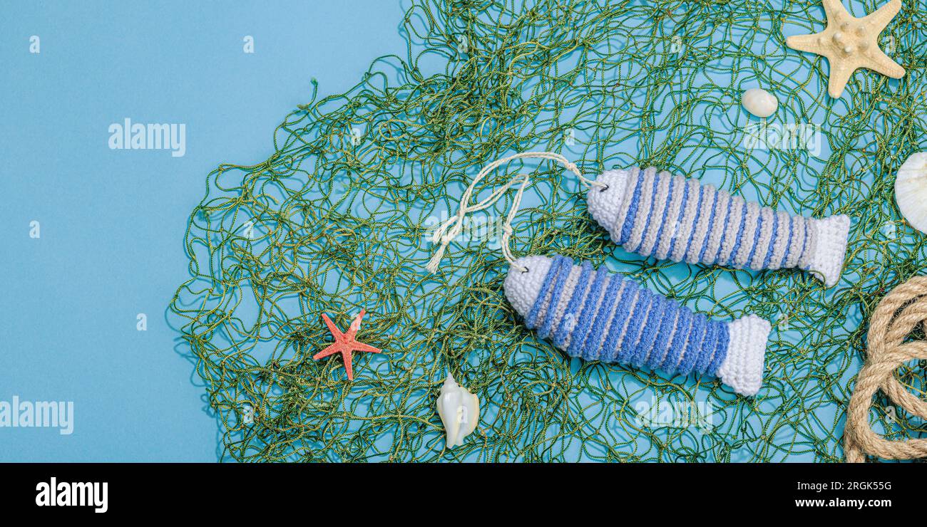 Handmade marine concept. Crocheted sardine fishes, nautical style. Fishing  net, traditional sea decor. Hard light, dark shadow, trendy blue background  Stock Photo - Alamy