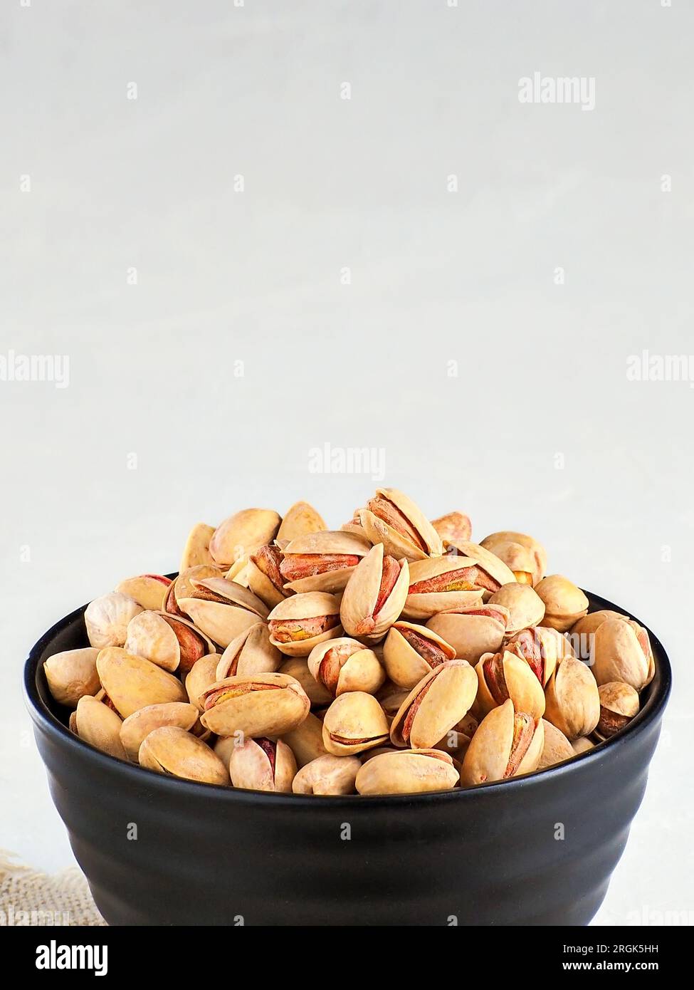 Pistachios in shell are poured into cup. Frontal front view with copy