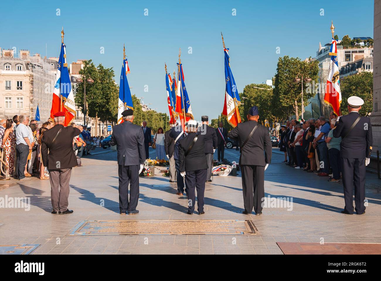 Group at Monument with Flags in Sunny Paris Stock Photo