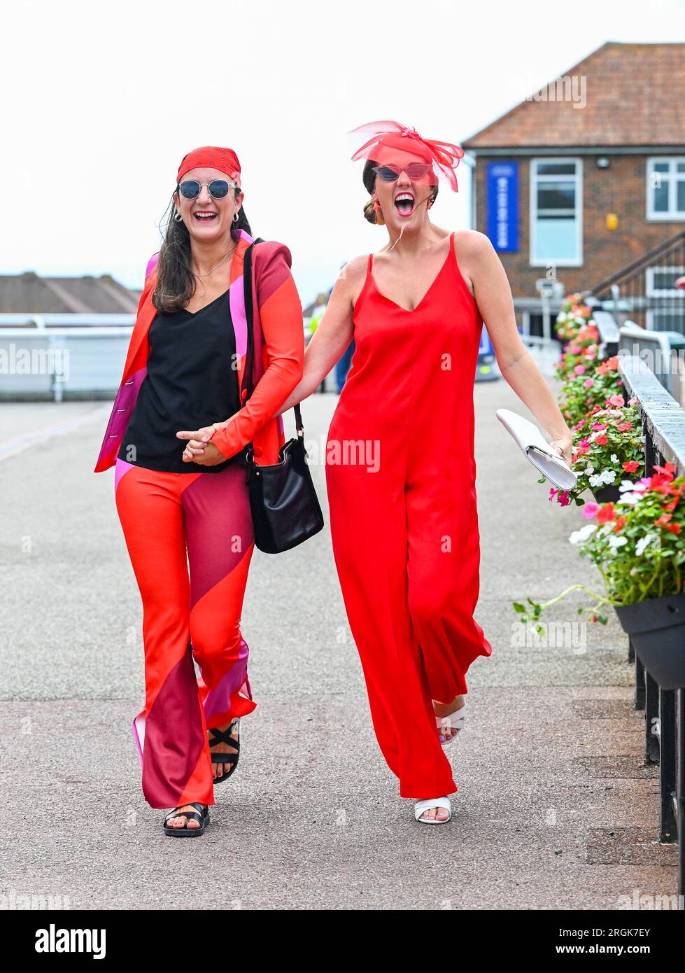 Brighton UK 10th August 2023 - Dimana  Popovska (left) and Grace Thornton in the red as they  enjoy the hot sunny weather at Brighton Races Ladies Day  during their Star Sports 3 day Festival of Racing    : Credit Simon Dack / Alamy Live News Stock Photo