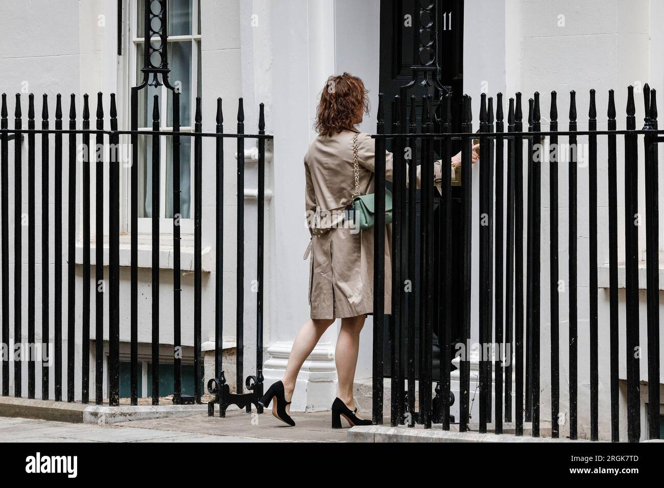 A female visitor or aide rings the doorbell at 11 Downing Street, where the Chancellor's office is located, London, UK Stock Photo