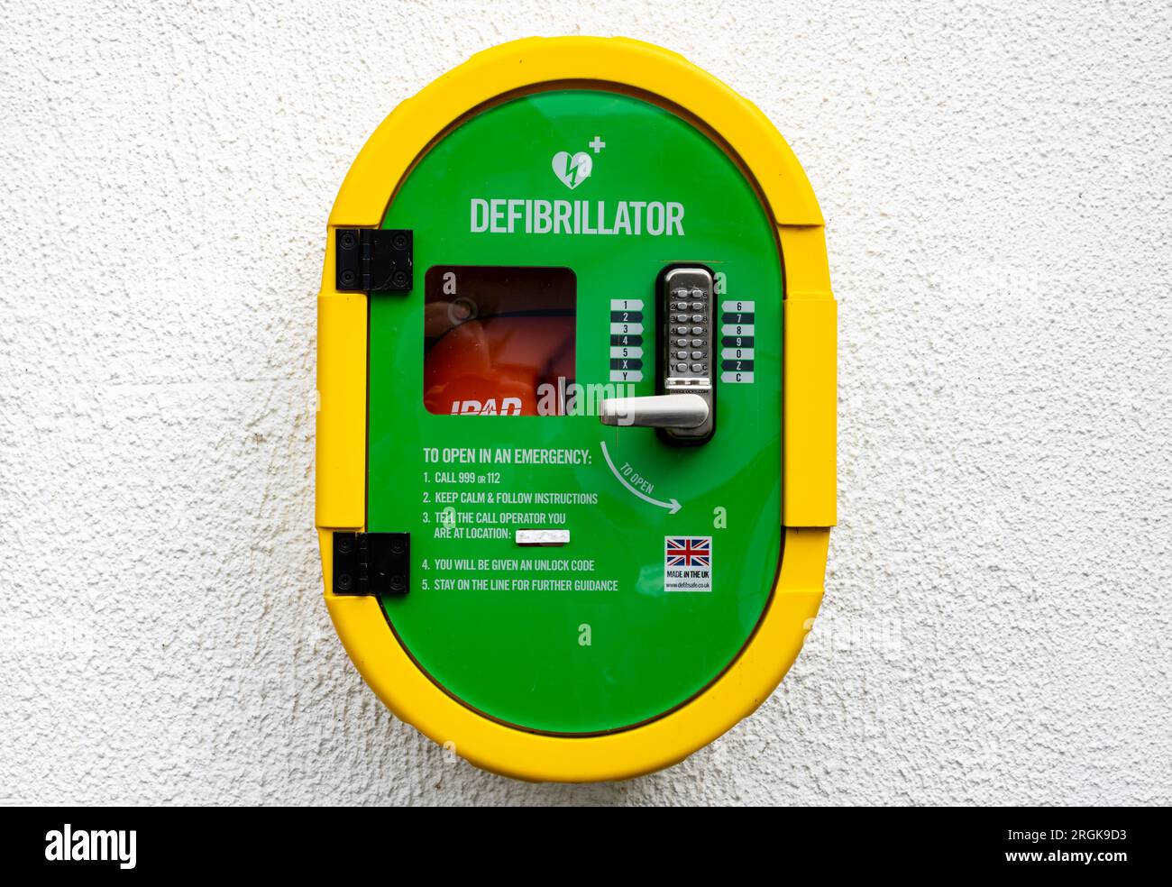 Landscape view against a white wall of an Automated external defibrillator, or AED kept where health professionals and first responders can use them Stock Photo