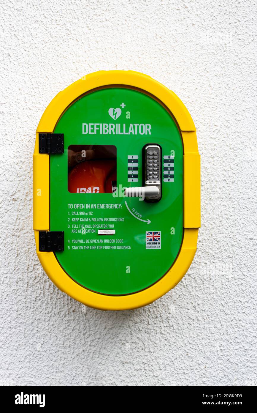 Portait  view against a white wall of an Automated external defibrillator, or AED kept where health professionals and first responders can use them Stock Photo