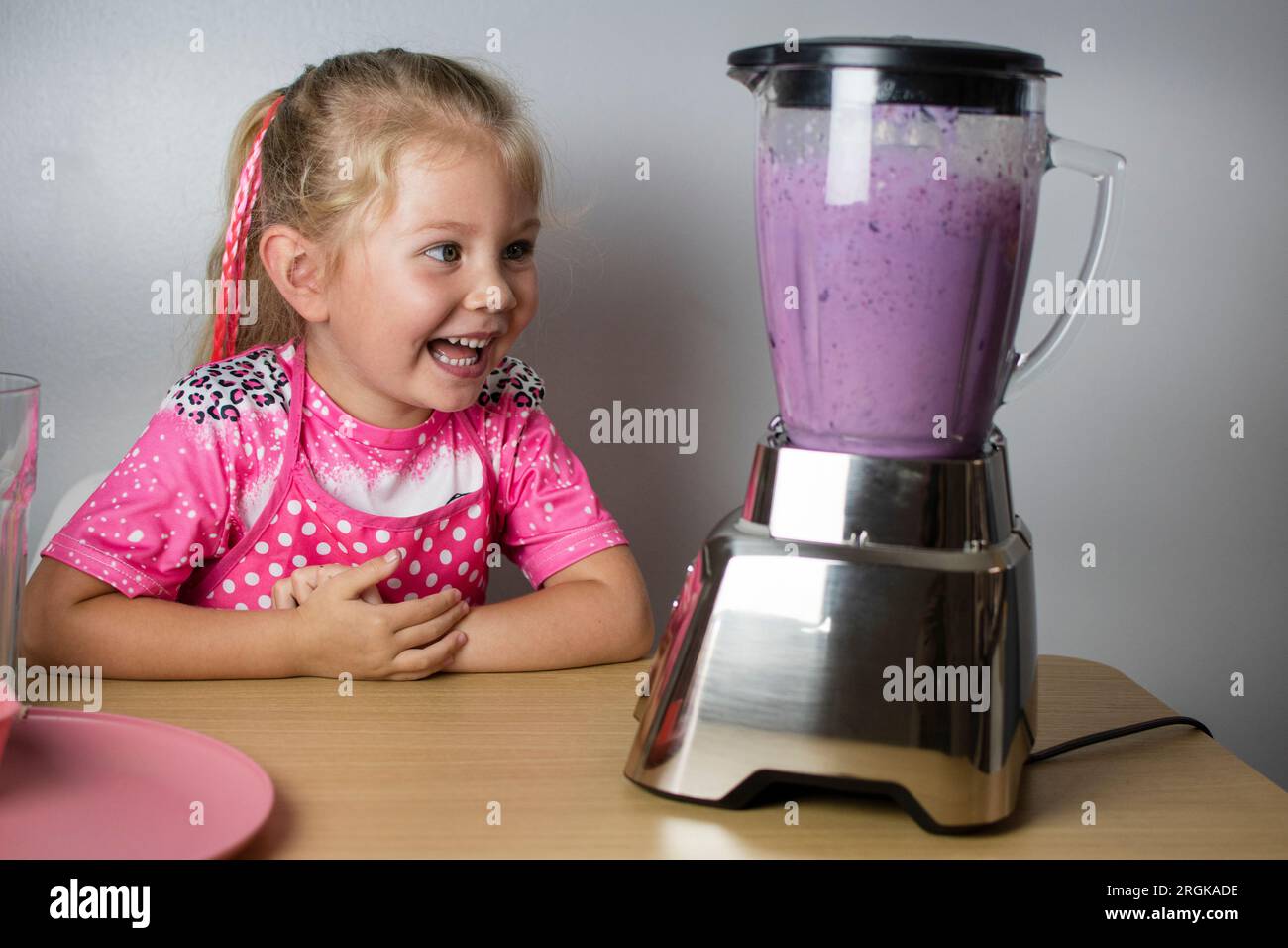 The happy Caucasian cute child is amused by the loud sound of the