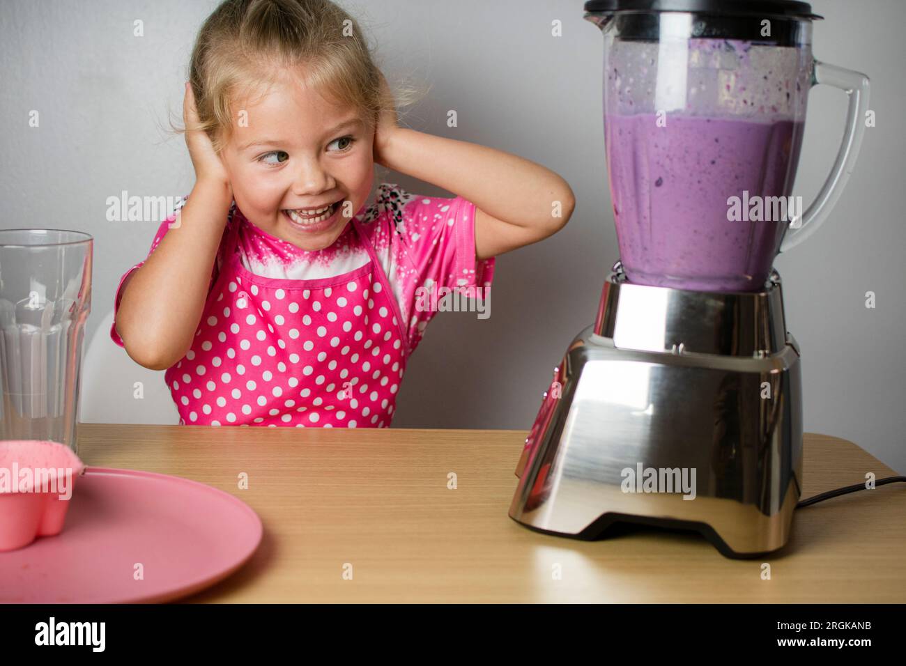 The happy Caucasian cute child is amused by the loud sound of the