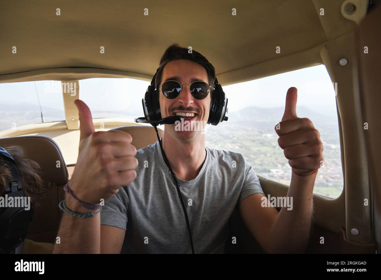 Stock photo of happy man wearing aviation headset enjoying light aircraft tour and looking at camera. Stock Photo