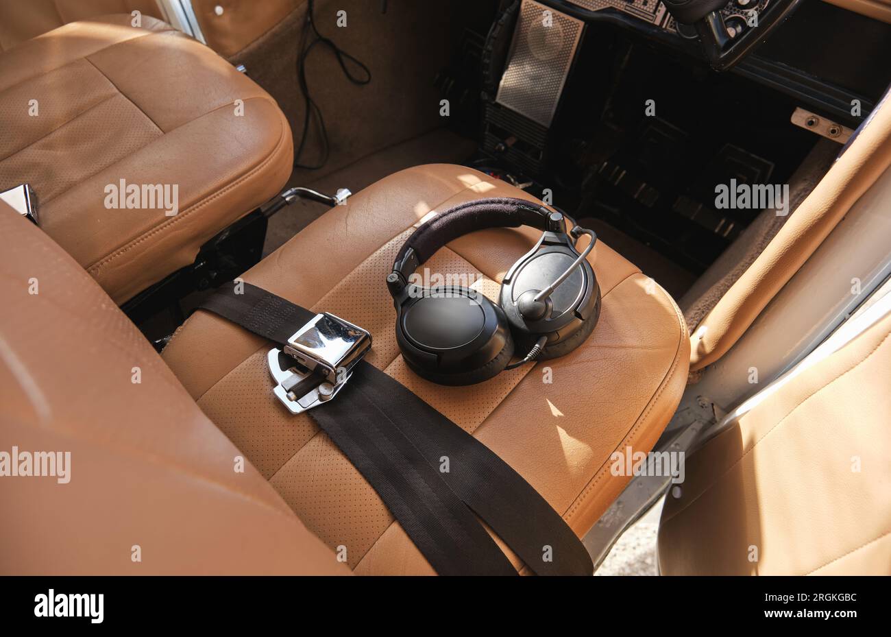 From above of modern headset placed on leather seat of small aircraft on sunny day Stock Photo