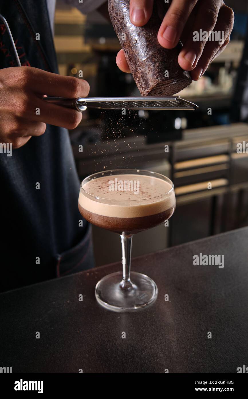 Crop anonymous bartender grating chocolate on delicious espresso