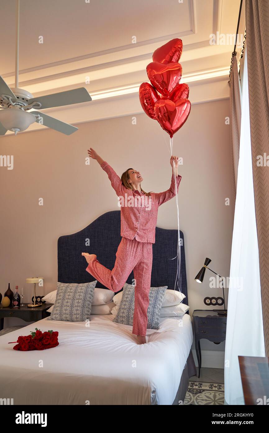 Side view of full body barefoot female in pink pajamas with bunch of