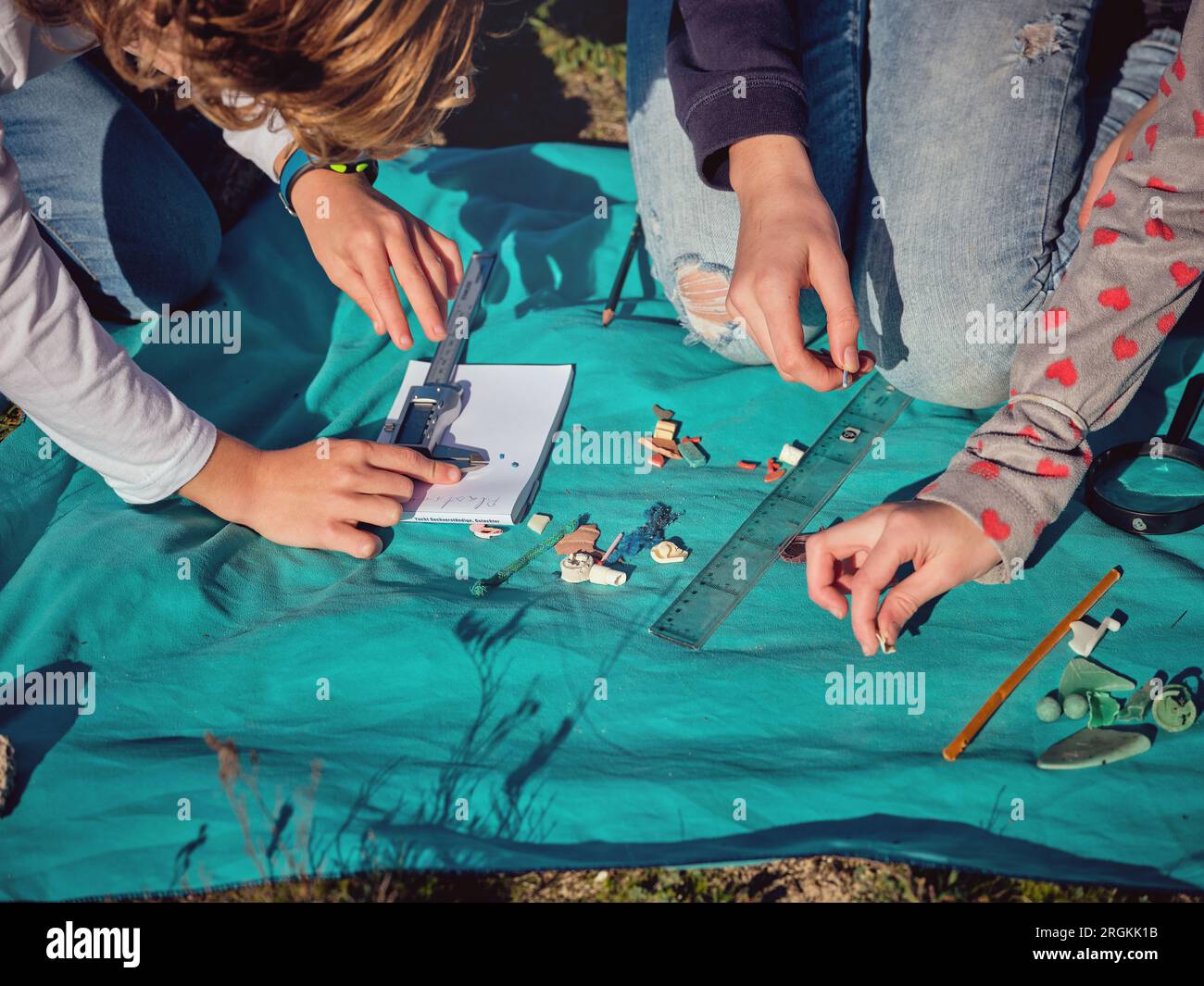 From above of crop preteen children measuring assorted picked up pieces ...