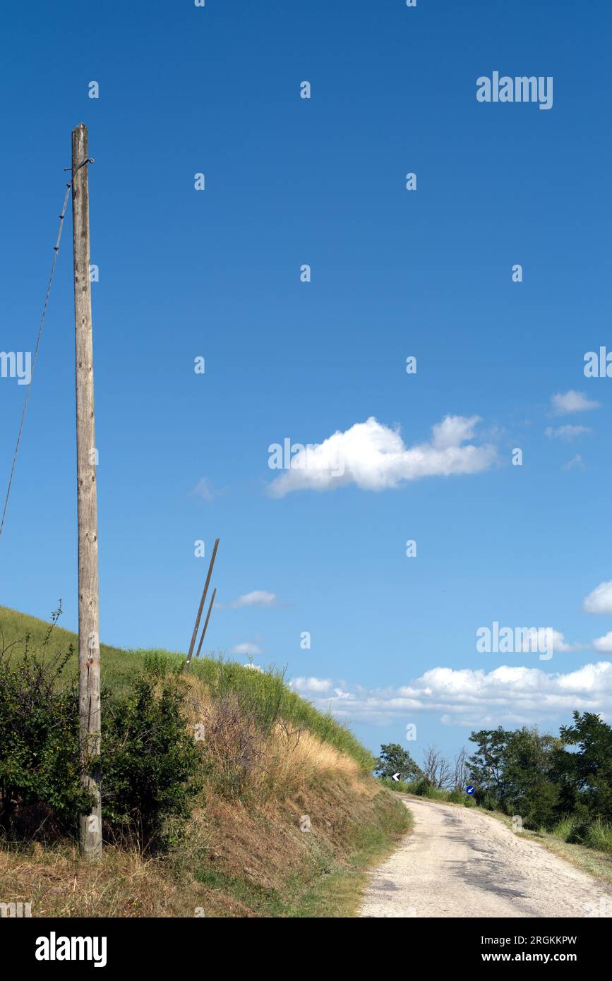 pali del telefono rotti accanto ad una strada di campagna Stock Photo