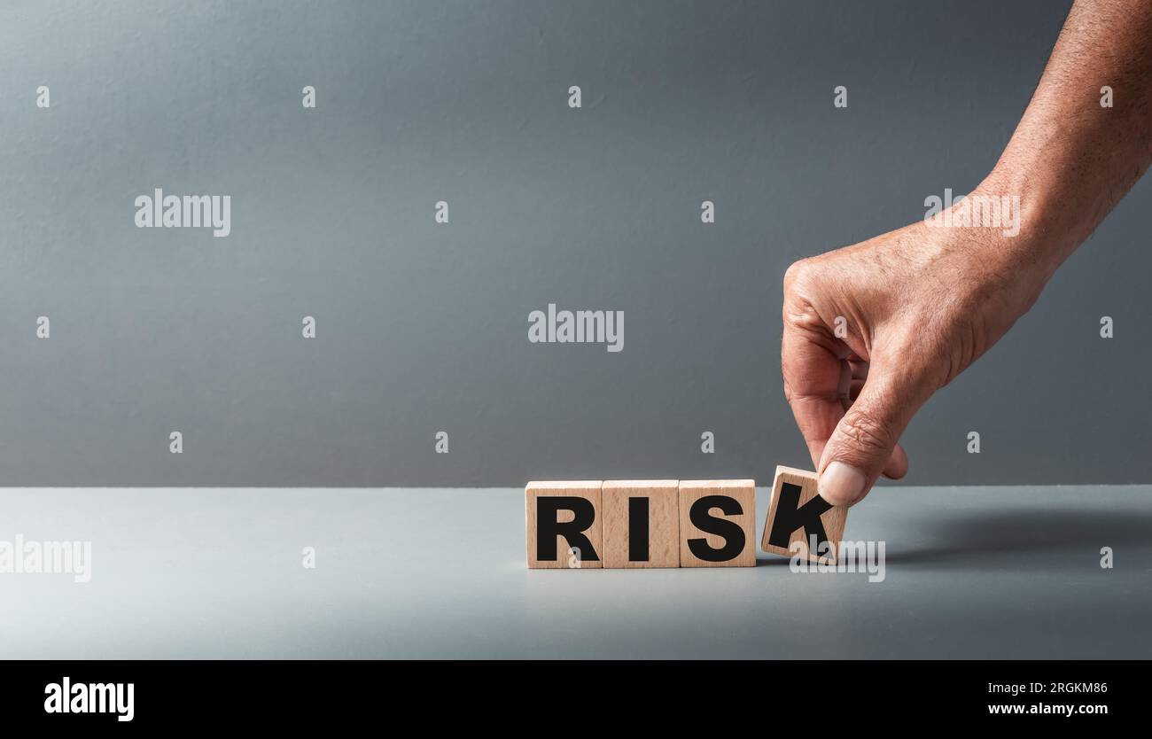 Hand holding wooden cubes with the word risk on a grey background concept of Risk management ,copy space . Stock Photo