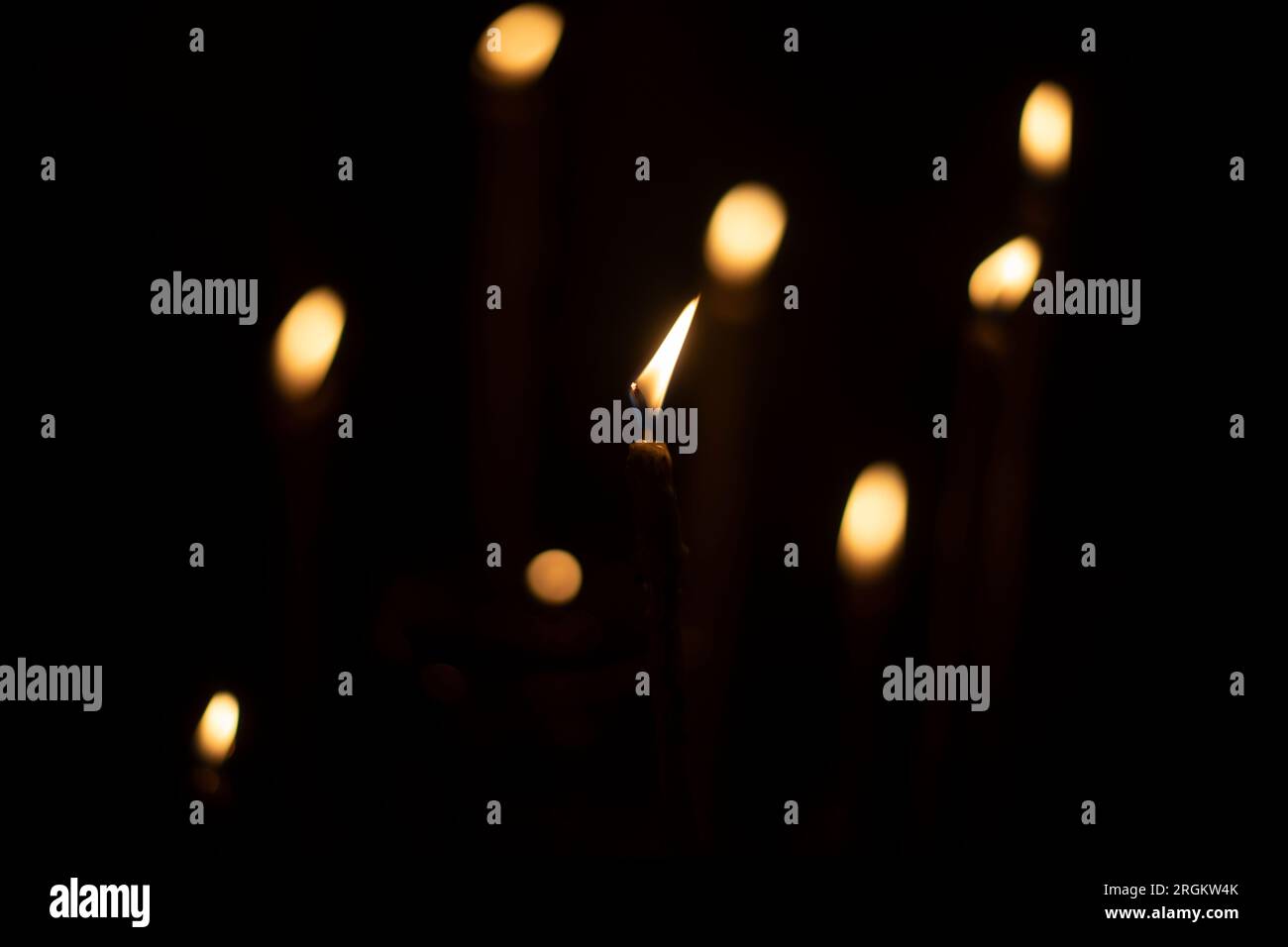 Candles burn in dark. Candle lights. Flames on black background. Yellow