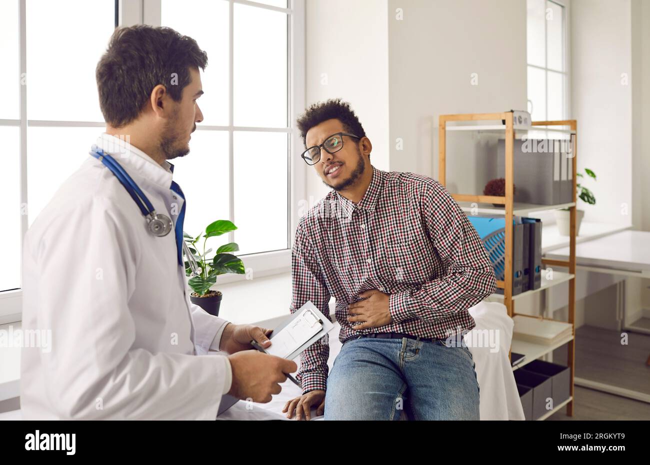 Young man with stomach ache and pain in his right side seeing doctor at hospital Stock Photo