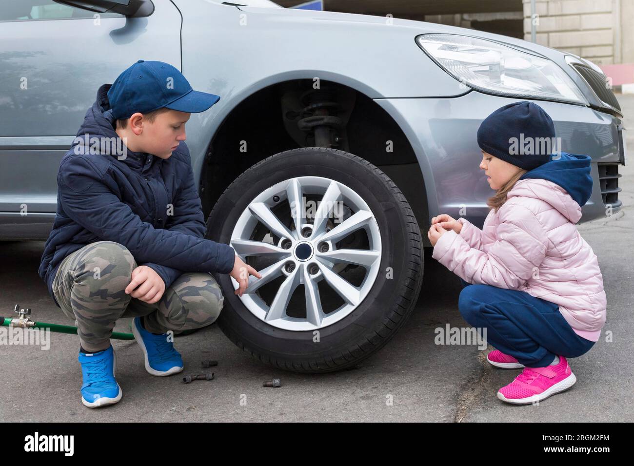 Boy and girl at a car service. Wheel replacement on a car, repair ...