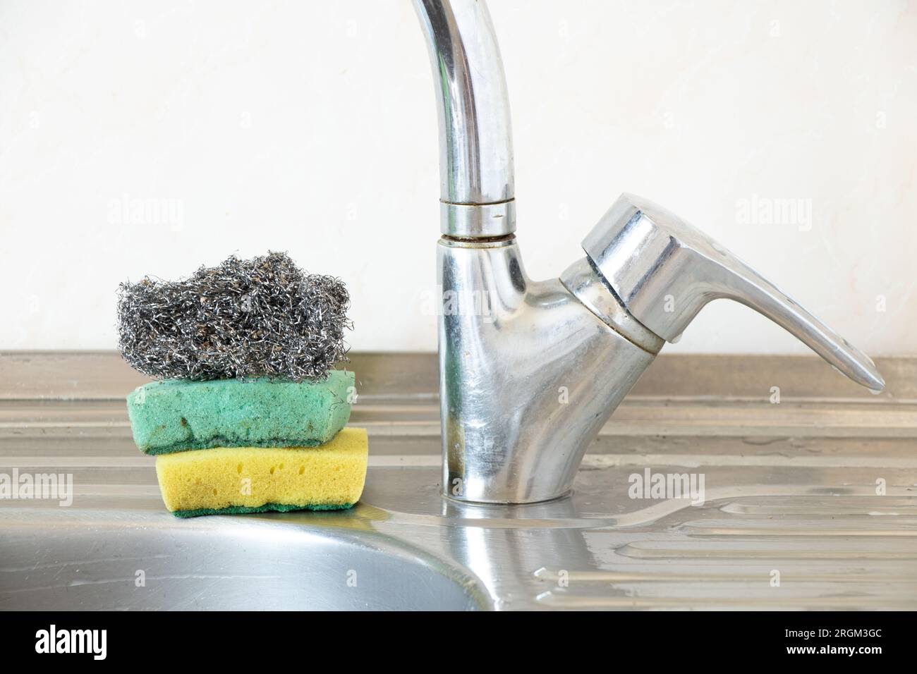 Dirty kitchen sponges and a metal ruff lie on the kitchen sink in the kitchen at home Stock Photo