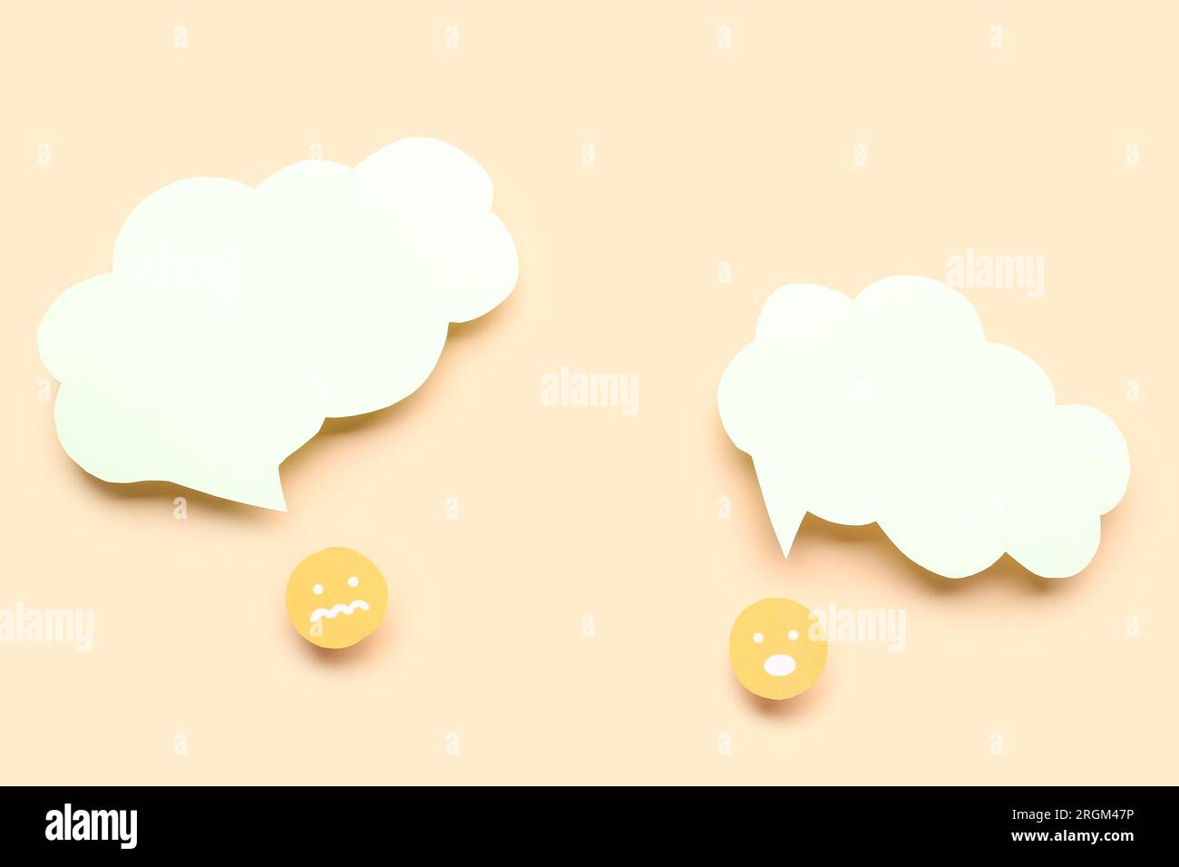 Paper faces with blank speech bubbles on beige background Stock Photo
