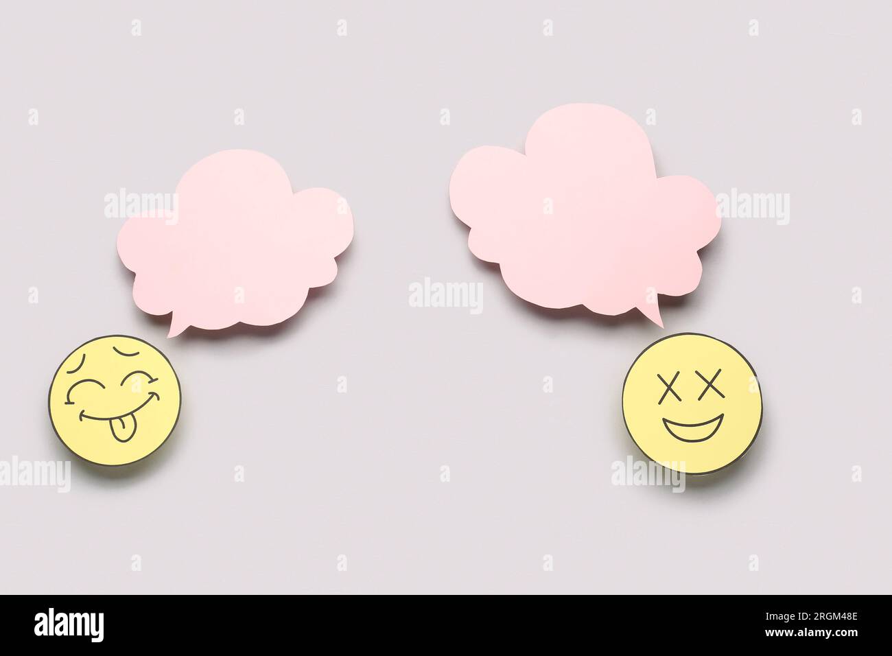 Paper faces with blank speech bubbles on grey background Stock Photo