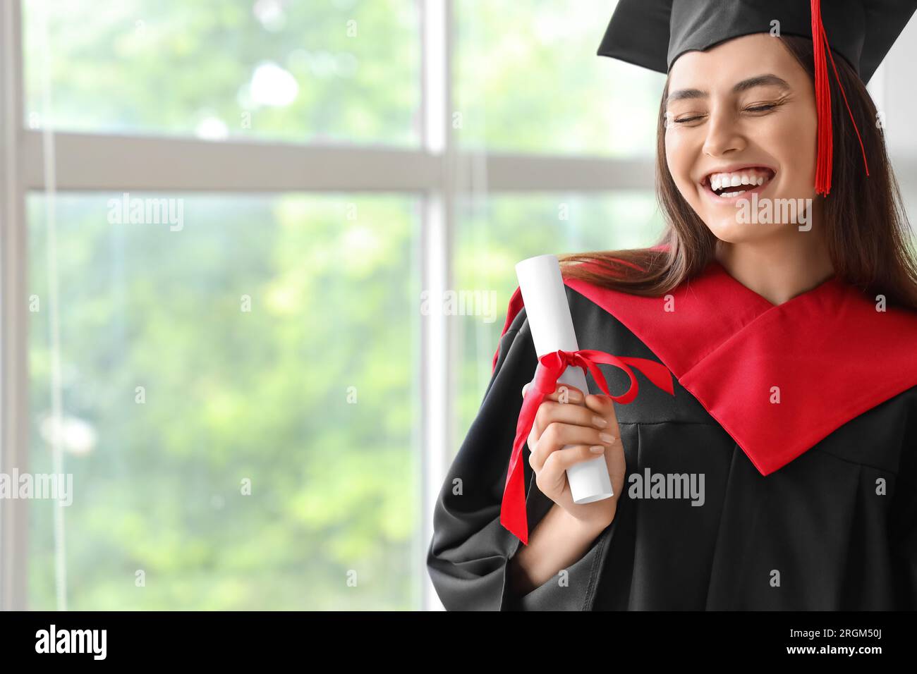 Female graduate student with diploma near window in room Stock Photo ...