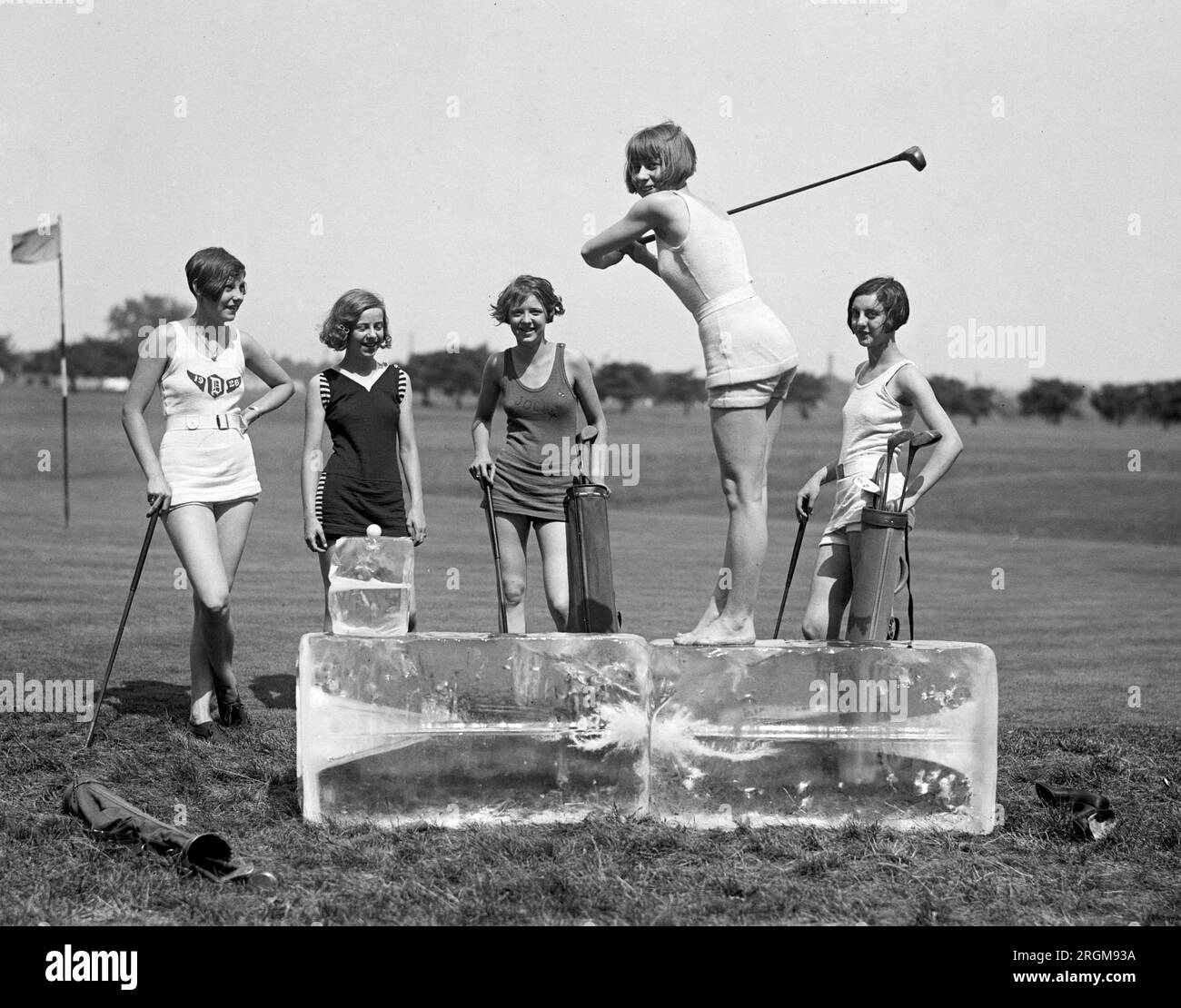 Woman golfer wearing a bathing suit standing on a block of ice hitting a golf ball ca. 1926 Stock Photo