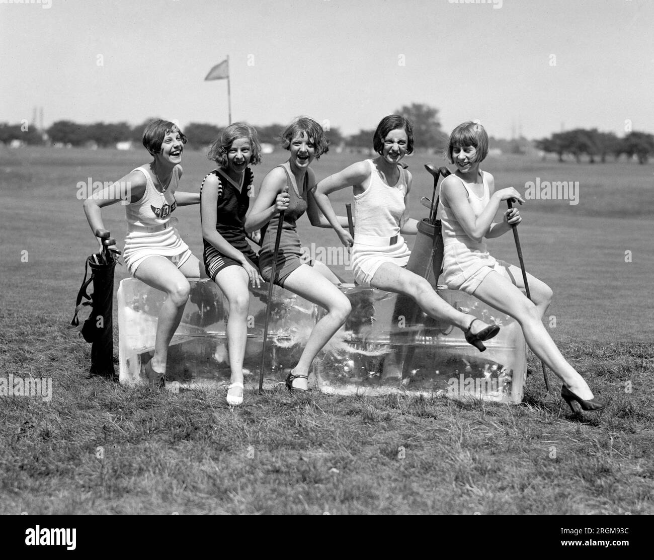 Women in bathing suits and holding golf clubs on a golf course, sitting on a block of ice ca. 1926 Stock Photo