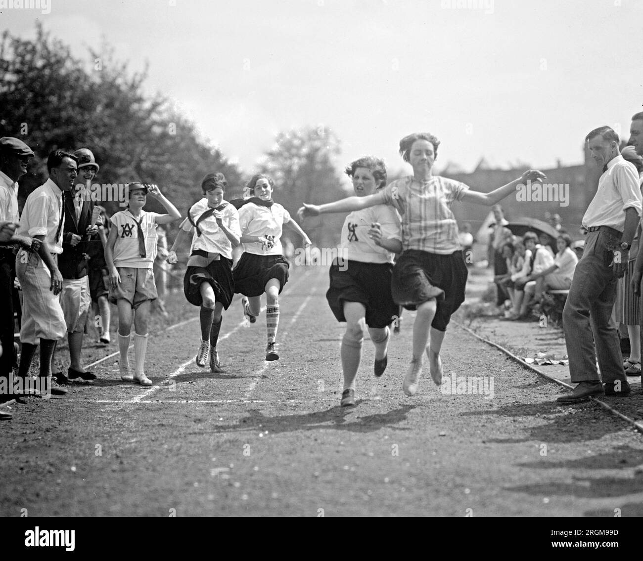 Girls running a relay and crossing the fiinish line during a playground