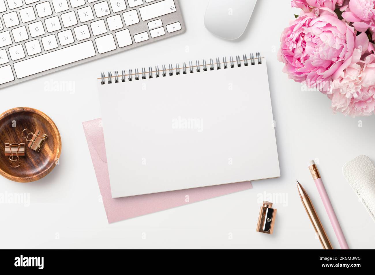 feminine workspace / desk with blank open notepad, keyboard, stylish office / writing supplies ...