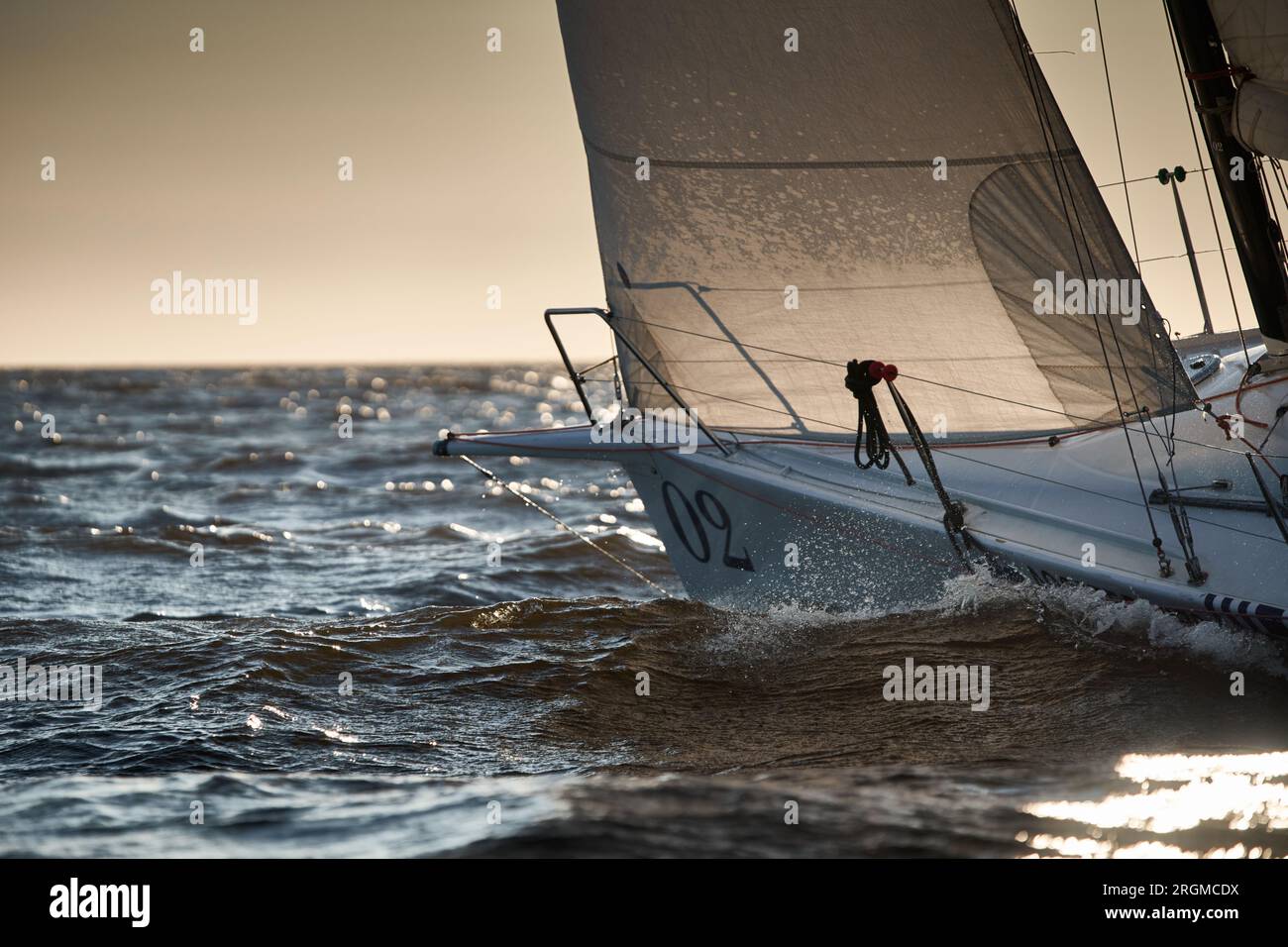 The view of sailboat is heeling at sunset, reflection of sun on water