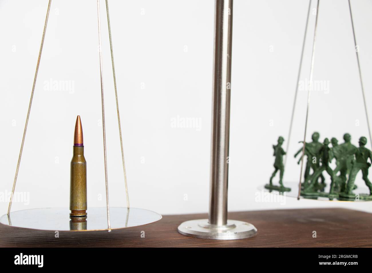 Plastic green soldiers and a bullet are on the scales, the weapon