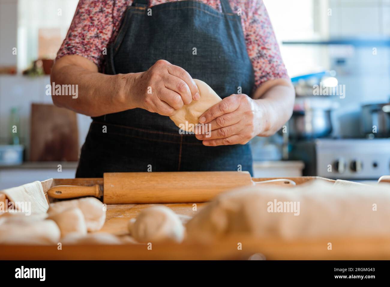 Skilled Latina Cook Creating Dough by Hand with Rolling Pin in Countryside Kitchen Scene Stock Photo