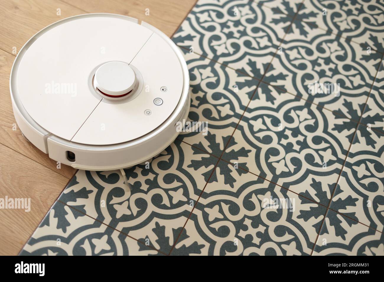 Wireless autonomous smart robotic vacuum cleaner is vacuuming floor with modern tiles at living