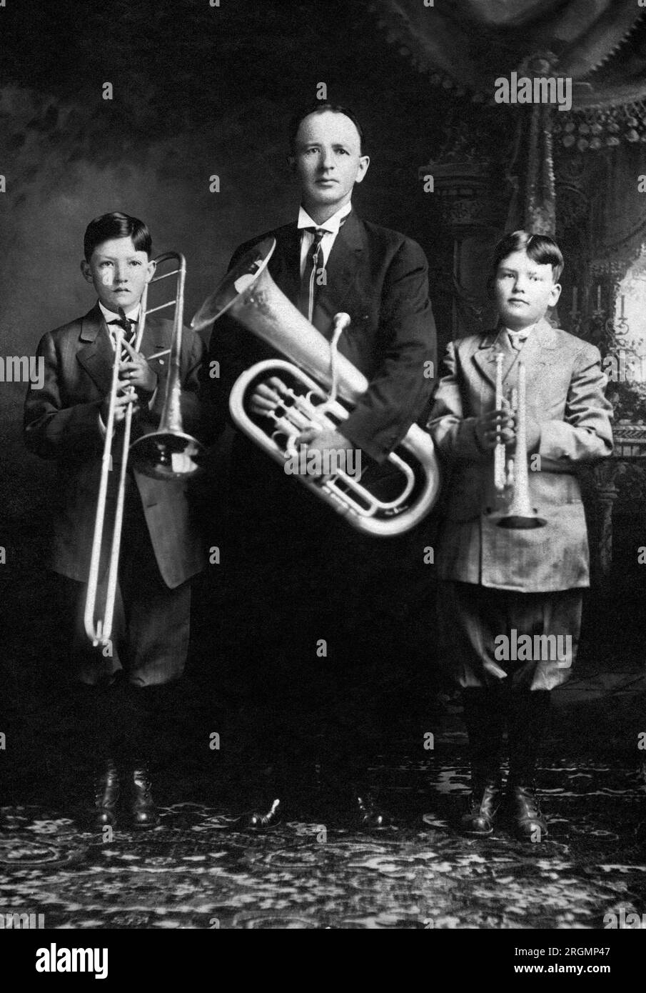 Portrait of Father holding Baritone Horn, and Two Sons, one with Trombone and one with Trumpet, White Hall, Illinois, USA, Cabinet Card, Olaf Holcomb, early 1900's Stock Photo