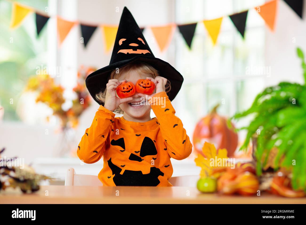 Child in Halloween costume. Kids trick or treat. Little boy with pumpkin lantern. Baby in witch hat. Autumn season holiday decoration. Stock Photo