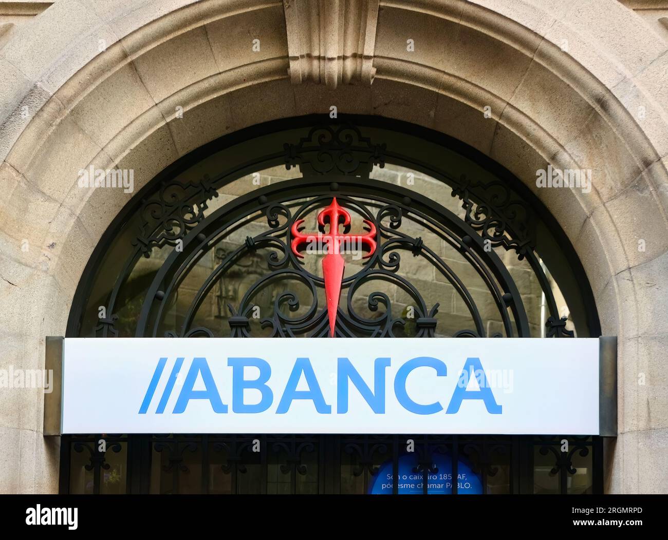 Cross of Saint James and Abanca Sign over the entrance to a bank branch in the historic city centre of Santiago de Compostela Galicia Spain Stock Photo
