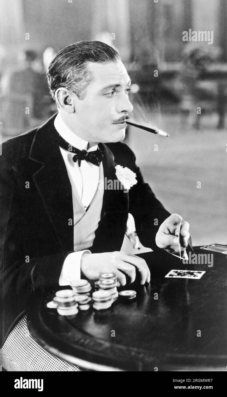Man, with cigarette holder in mouth, playing cards ca. 1930 Stock Photo