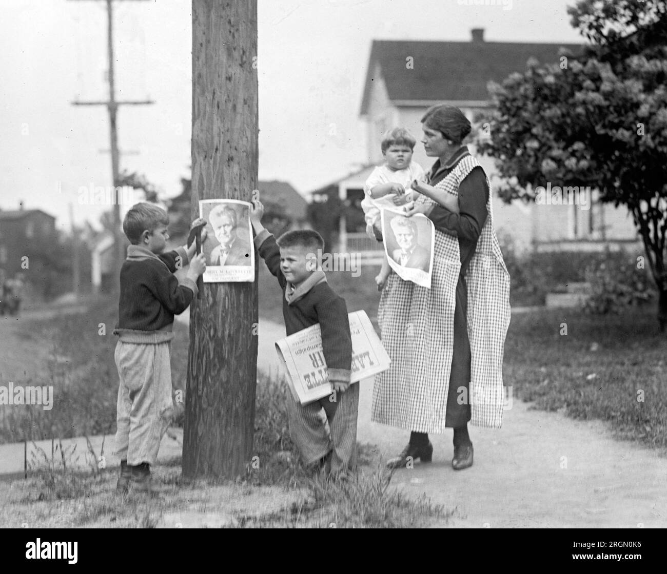 Mrs. LaFollette and her children posting handbills / posters of her