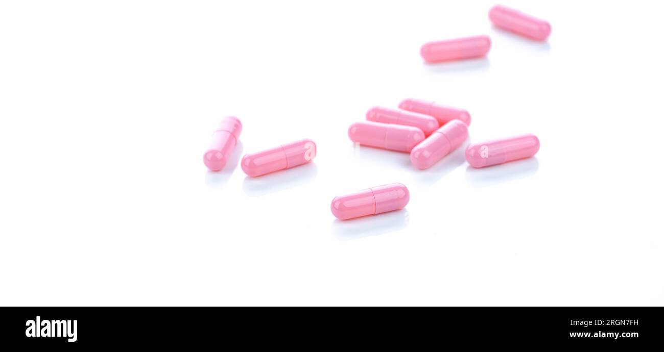 Pink capsule pills on white background. Pharmaceutical industry