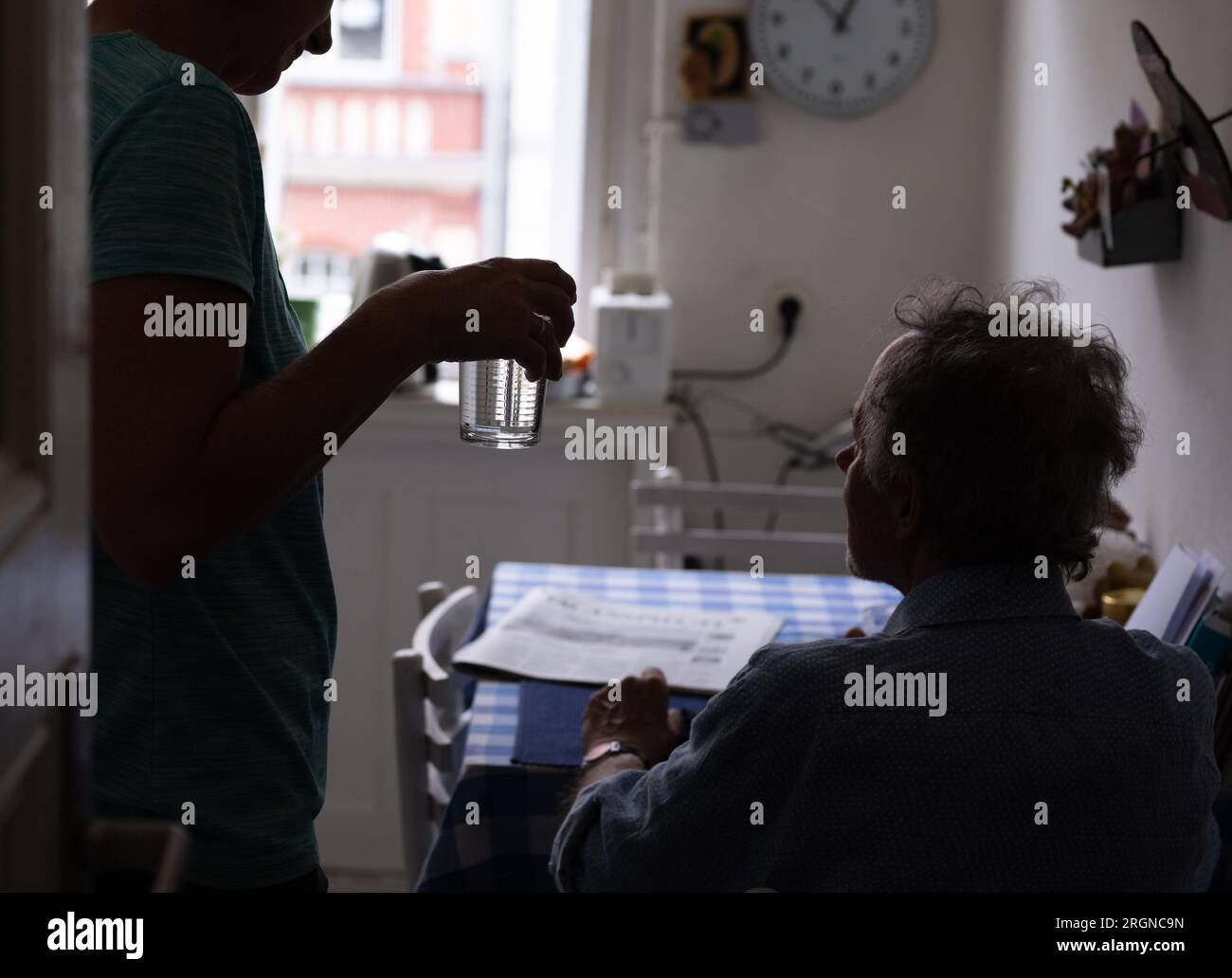 Berlin, Germany. 31st July, 2023. Nurse Ramona Rössner hands a glass of water to her patient Andreas Seltzer, who is in need of care, during a home visit. (to dpa-KORR 'You drink, I drink' - How heat endangers old people) Credit: Monika Skolimowska/dpa/Alamy Live News Stock Photo