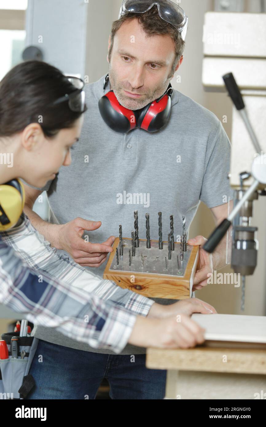 female apprentice choosing drill bit for machinery Stock Photo