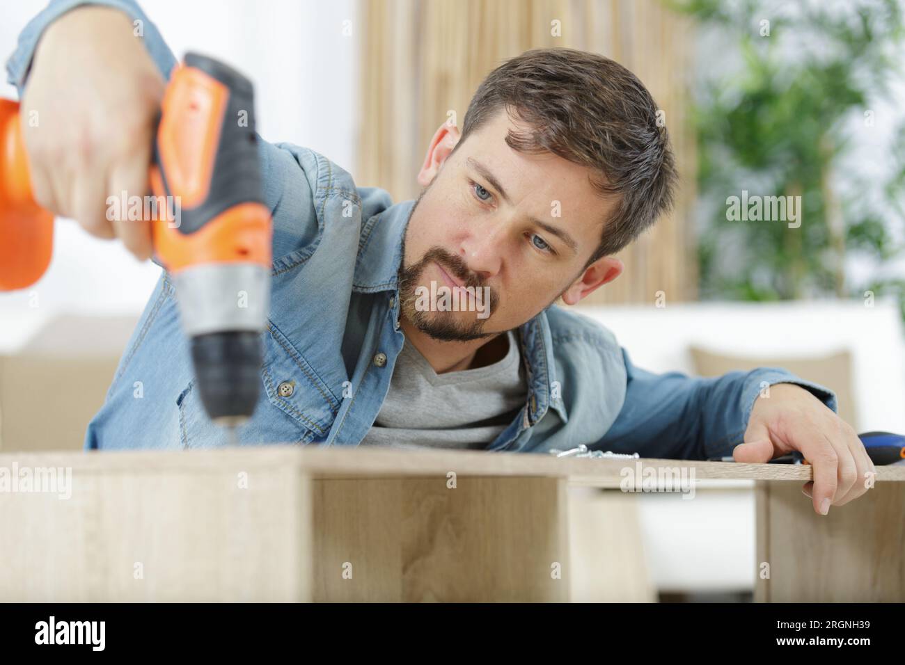 worker drills a hole when assembling furniture Stock Photo