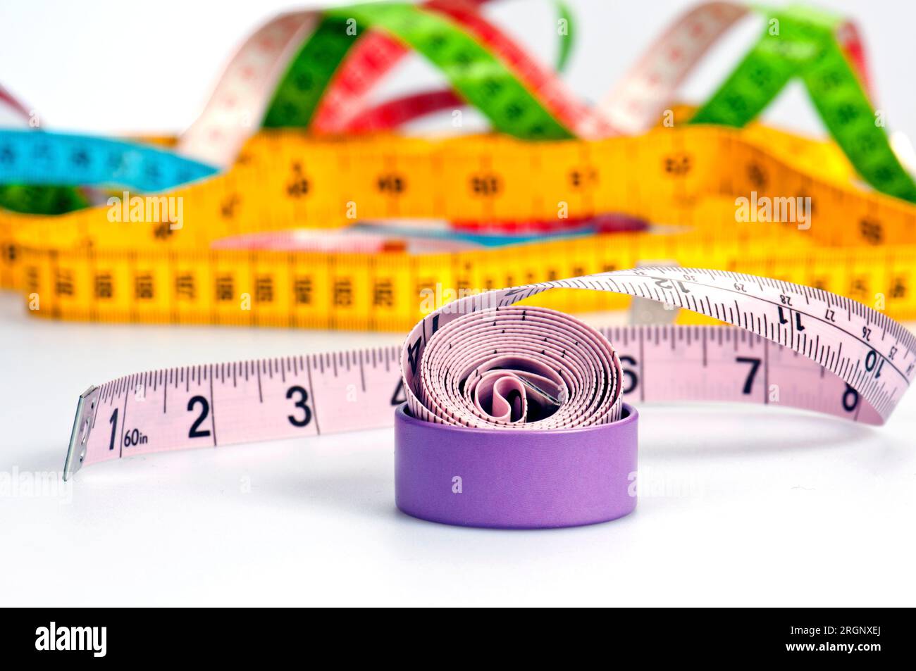 Unfolded white tape measure, White measuring tape isolated on pink