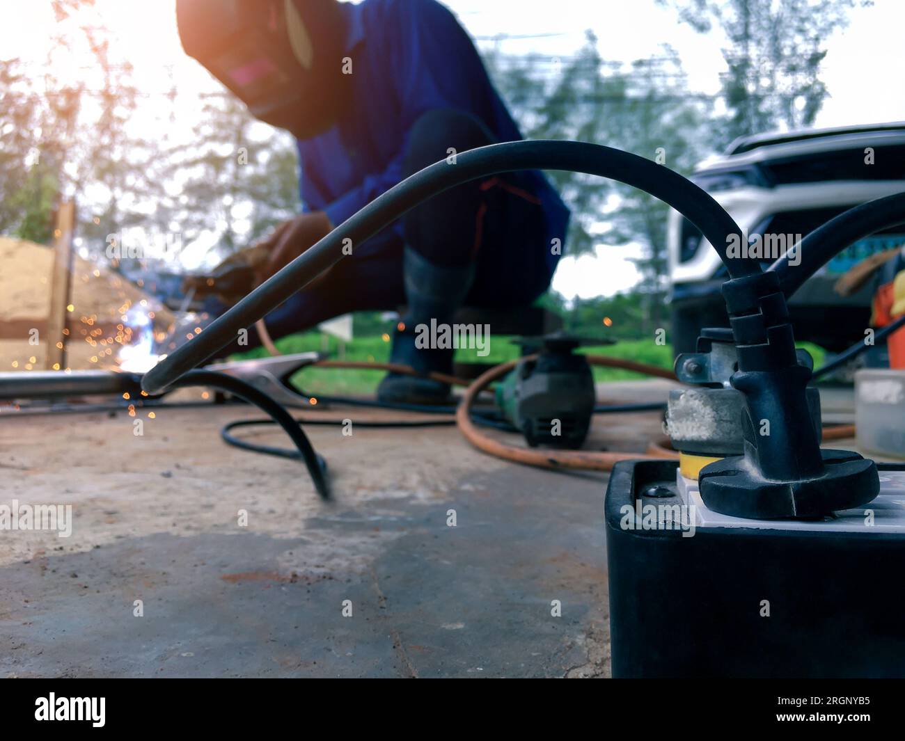 Close up power socket with a background of a worker welding metal for ...