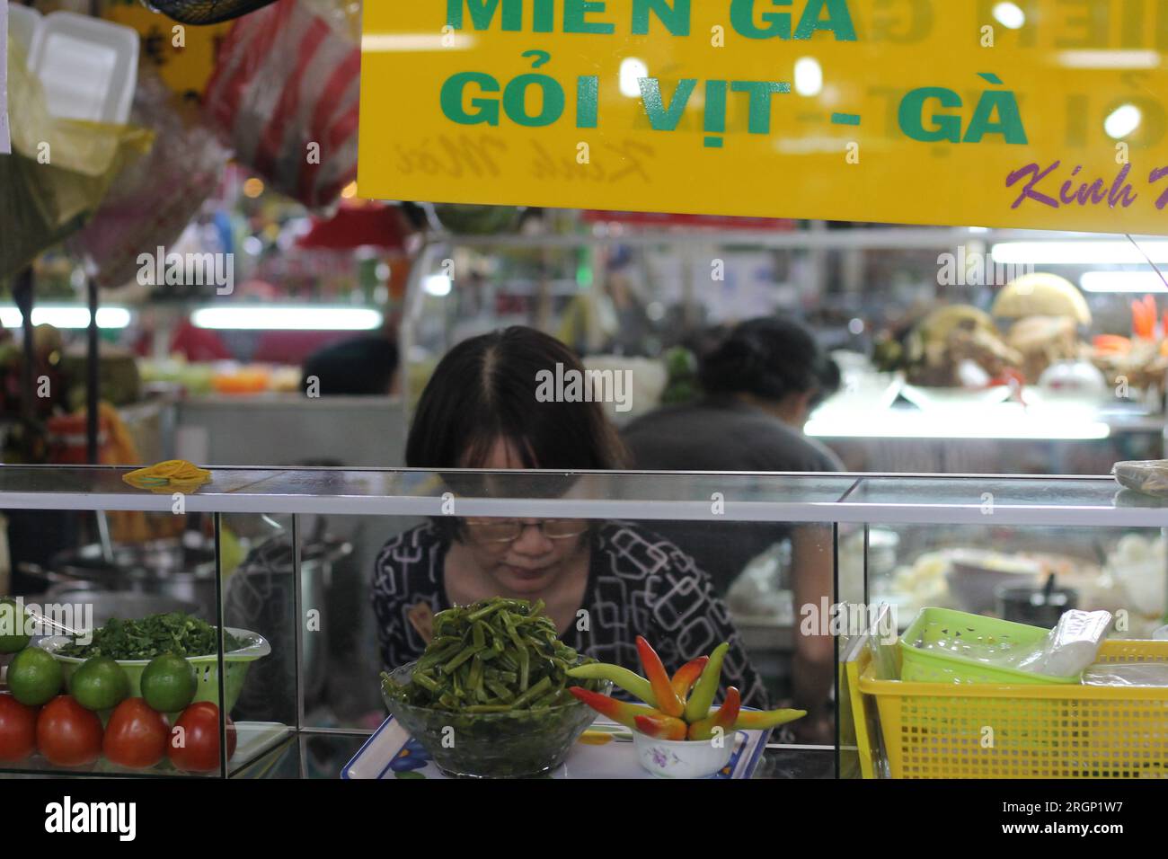 A busy market in Vietname, obscured face serving fresh vegetables Stock Photo