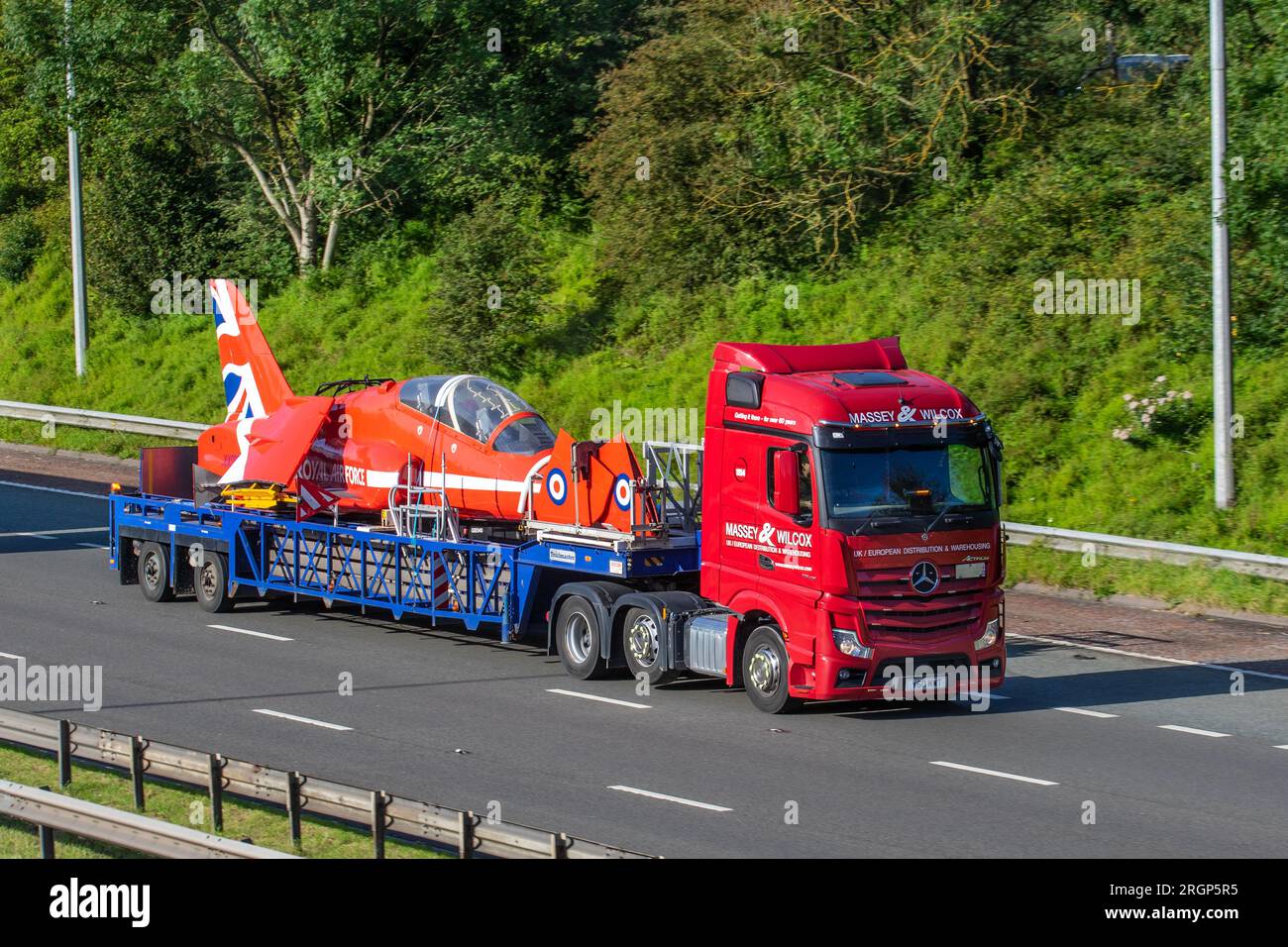 Parbold, Lancashire. UK  Weather 11 Aug 2023, A disassembled Royal Air Force Aerobatic Team distinctive Hawk jet travelling on Massey Wilcox HGV en route to Blackpool for the weekend Airshow. Usually seen arcing through the skies it is unusual to see the jet being transported to an Air Tattoo on a low-loader Mercedes Benz Diesel 12809 cc midlift lorry. Credit; MediaWorldImages/AlamyLiveNews Stock Photo