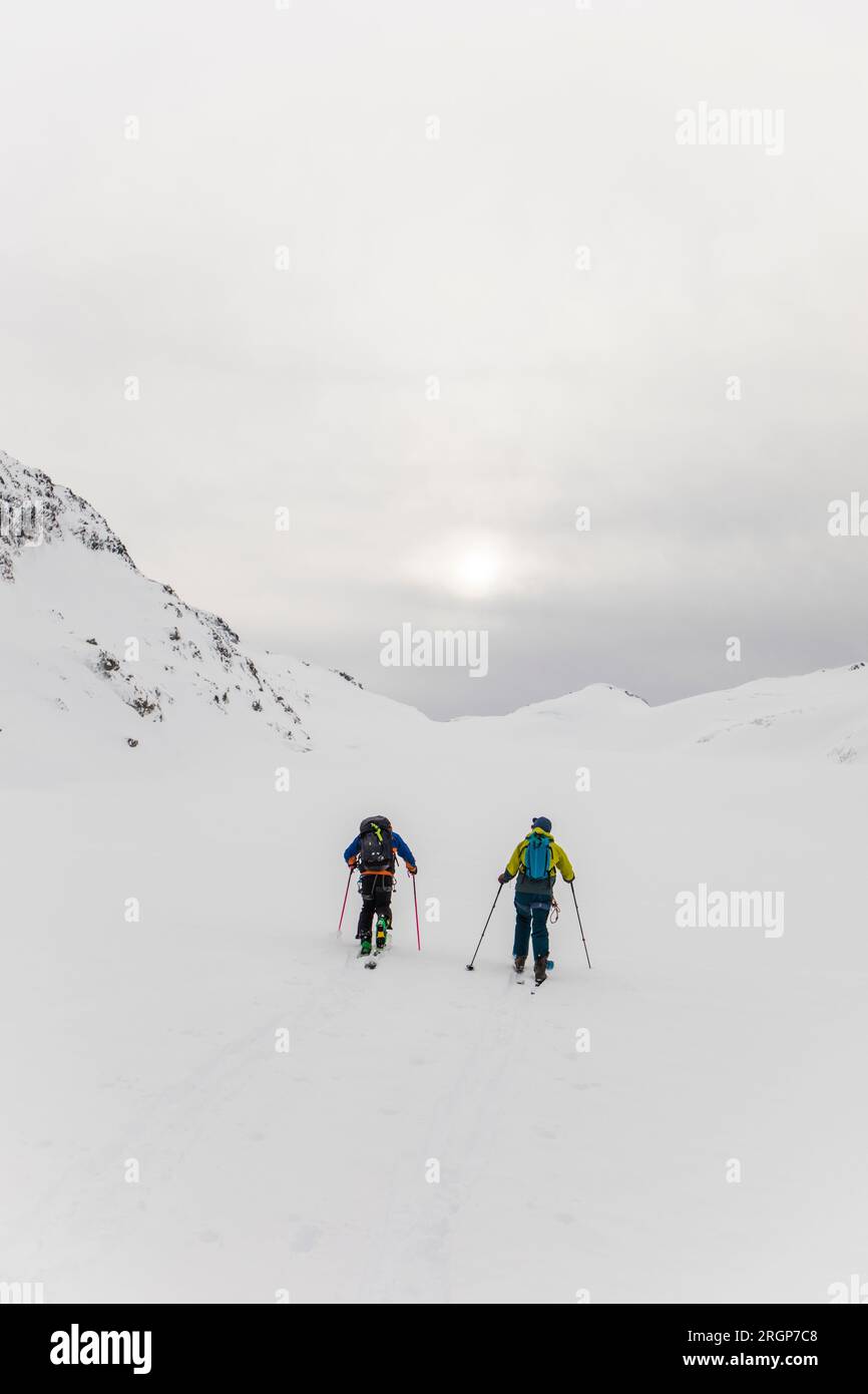 Rear view of two men with backpacks on ski touring in mountains Stock Photo