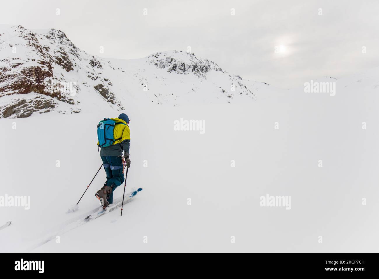 Rear view of man ski touring up glacier in B.C. Canada Stock Photo