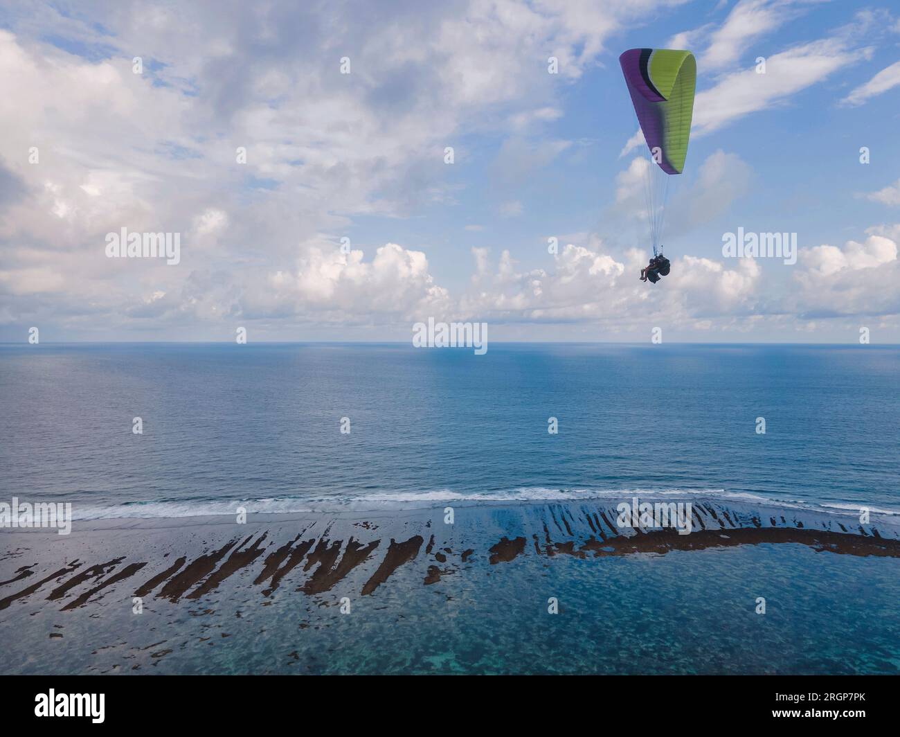 Paraglider soaring high above the sea at sunny day Stock Photo