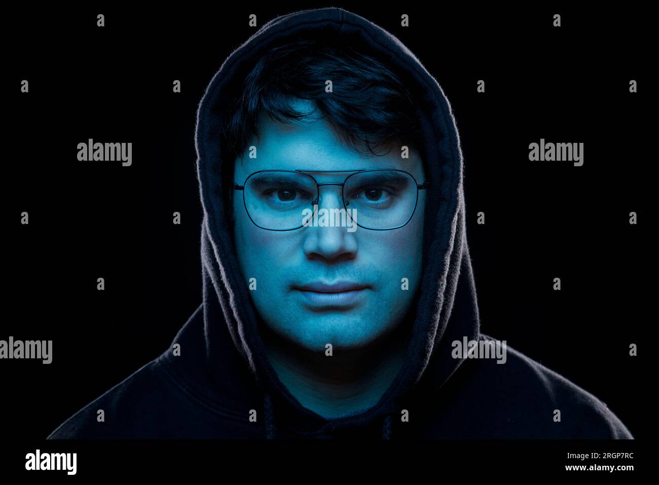 Portrait of a man with glasses lit with the blue light of a screen Stock Photo