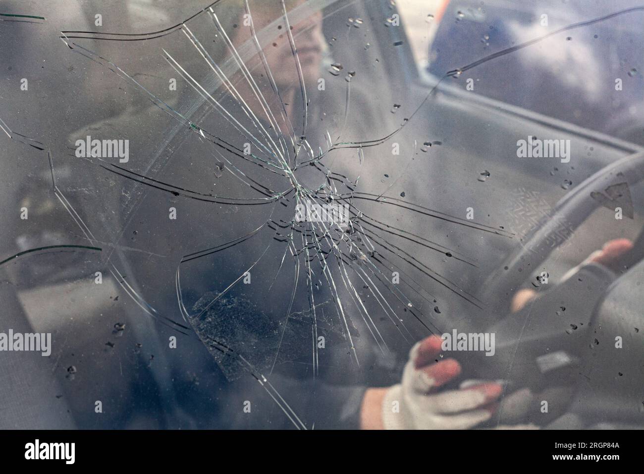 Cracks on glass of machine. Driver of car behind broken window. Stock Photo