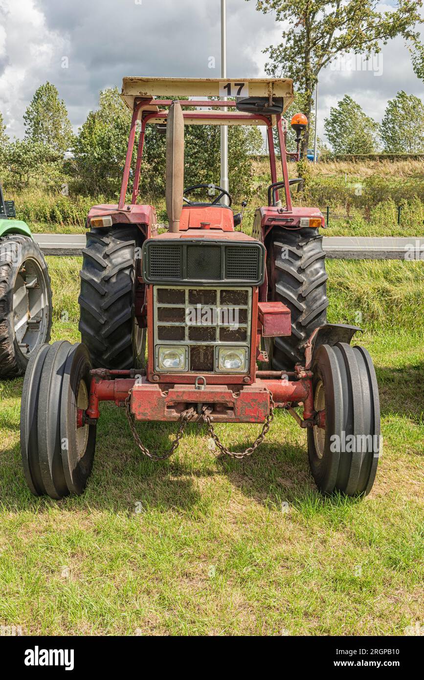 red tractor is parked on a pasture Stock Photo - Alamy
